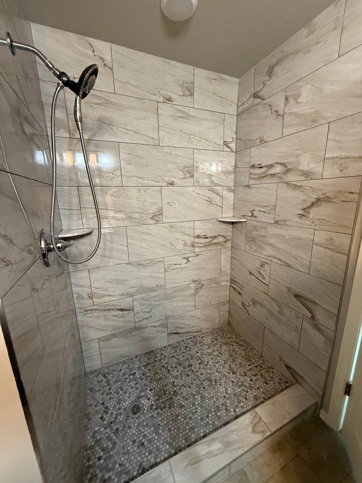 Hand shower on a slide bar and corner shelves in the Bixby walk-in shower