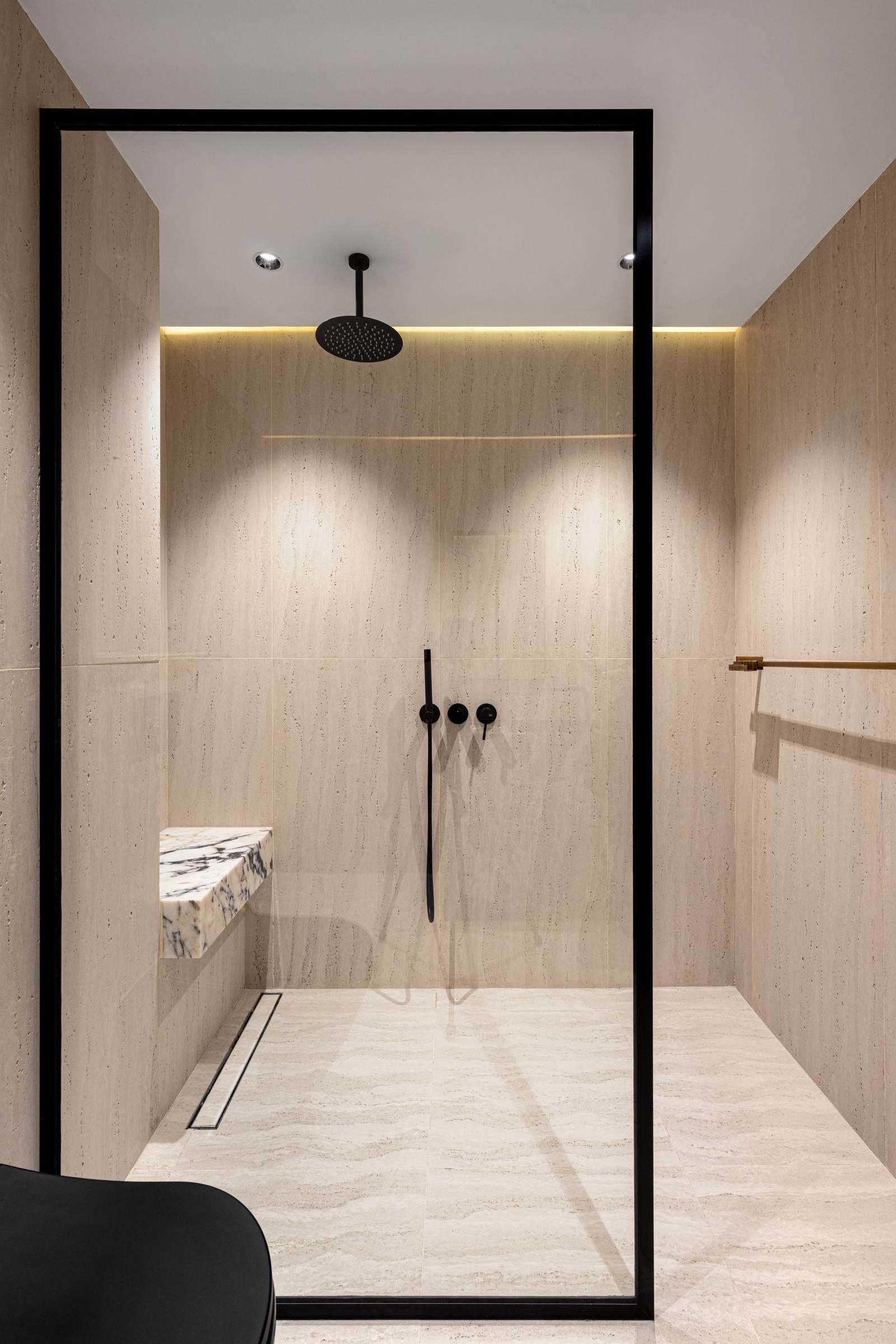Curbless walk-in shower with wood-look tile, a linear drain, a ceiling rain head and matte black controls