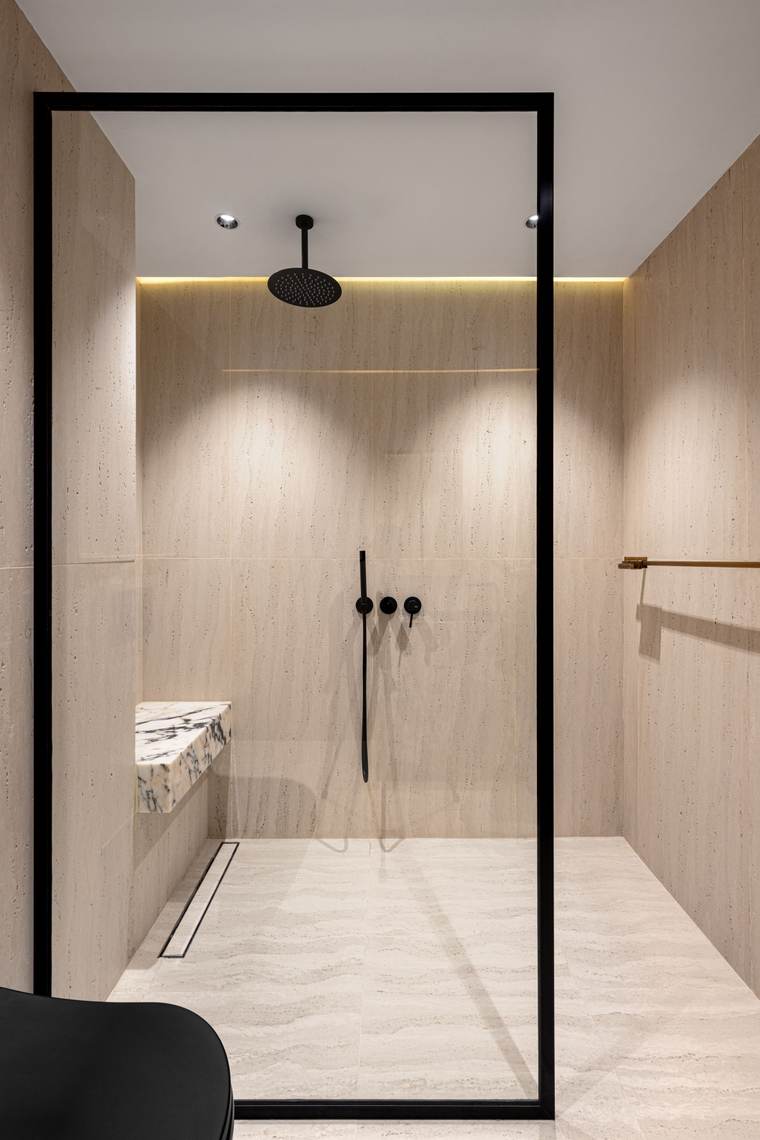 Walk-in shower with wood-look tile, a corner bench, and matte black fixtures