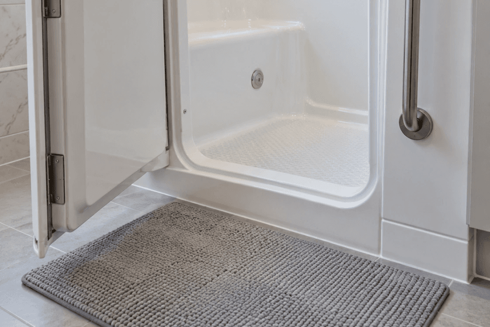 Walk-in tub with its full-height door swung open, showing the low threshold, the textured floor and a grab bar beside the door
